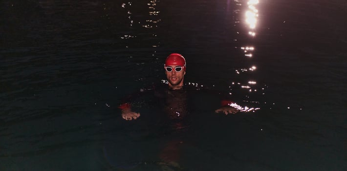 A determined professional triathlete undergoes rigorous night time training in cold waters, showcasing dedication and resilience in preparation for an upcoming triathlon swim competition photo