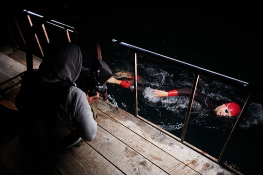 Videographer taking action shot of triathlon swimming athlete at night photo