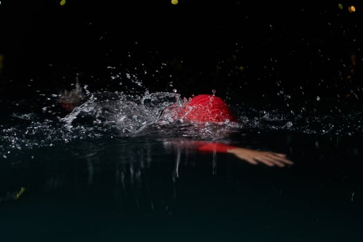 A determined professional triathlete undergoes rigorous night time training in cold waters, showcasing dedication and resilience in preparation for an upcoming triathlon swim competition photo