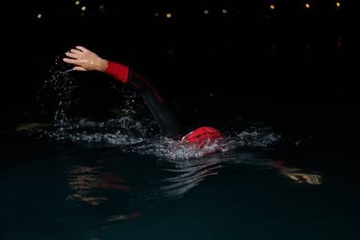 A determined professional triathlete undergoes rigorous night time training in cold waters, showcasing dedication and resilience in preparation for an upcoming triathlon swim competition photo