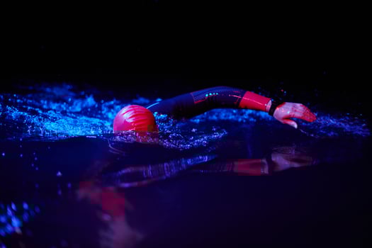 Authentic triathlete swimmer having a break during hard training on night neon gel light photo