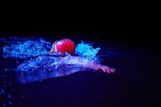 Authentic triathlete swimmer having a break during hard training on night neon gel light photo
