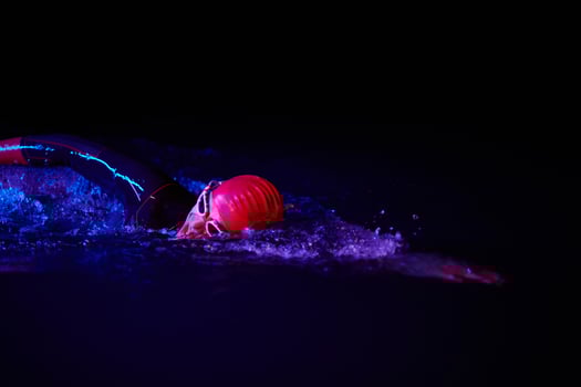 Authentic triathlete swimmer having a break during hard training on night neon gel light photo