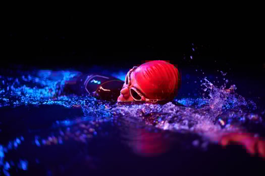 Authentic triathlete swimmer having a break during hard training on night neon gel light photo