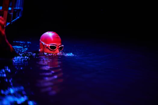 Authentic triathlete swimmer having a break during hard training on night neon gel light photo