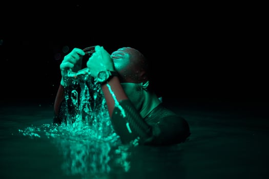 Authentic triathlete swimmer having a break during hard training on night neon gel light photo