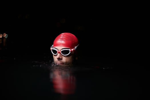 A determined professional triathlete undergoes rigorous night time training in cold waters, showcasing dedication and resilience in preparation for an upcoming triathlon swim competition photo