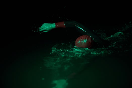 Authentic triathlete swimmer having a break during hard training on night neon gel light photo