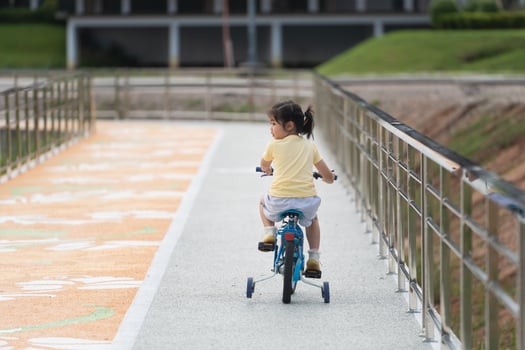 Back side view of asian baby girl child learning to ride bicycle in the park garden. Education concept for kid practiice cycling at park, baby sport concept. photo
