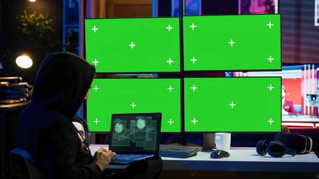 Man writing code on laptop in front of isolated screen PC monitors, trying to get past security systems. Hacker using chroma key computer and notebook to make scripts that can hack devices, camera A photo
