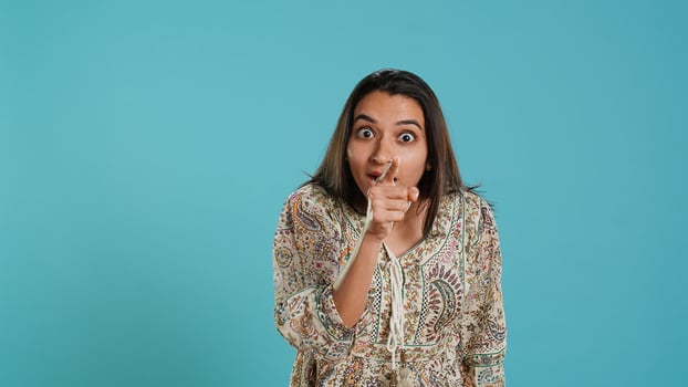 Irked indian woman fighting with boyfriend, doing scolding gesturing, isolated over studio background. Outraged wife arguing with husband during conversation, doing angry hand gestures, camera A photo