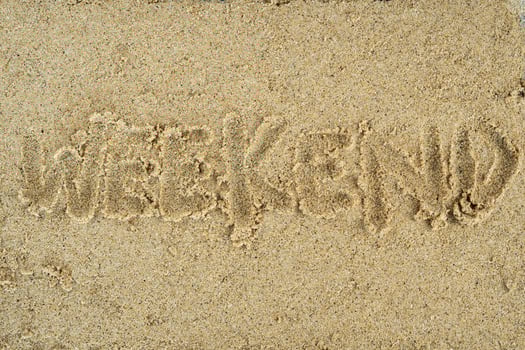 weekend hand writing on sand background photo