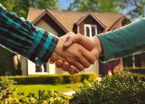 Close up of handshake with house for sale in background photo