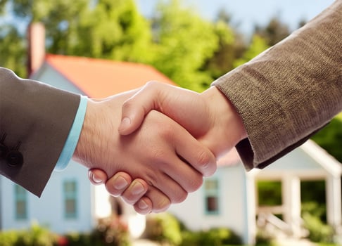 Close up of handshake with house for sale in background photo