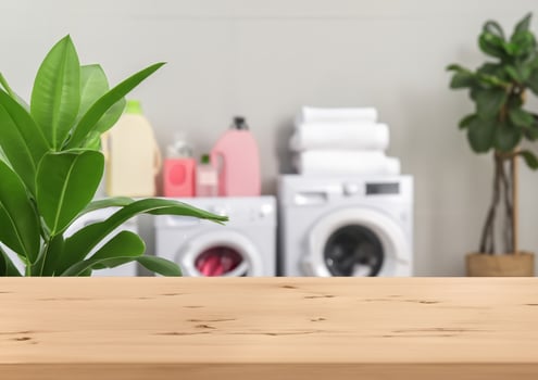 Wood table for display products and blurred laundry room with green plants photo