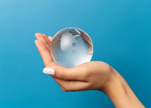 Woman hand holding a earth glass sphere on blue photo