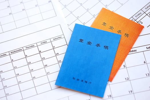 Japanese pension insurance booklets on table with calendar. Blue and orange pension book photo