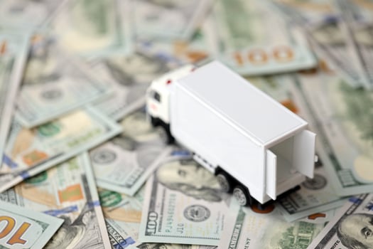 Delivery truck on hundred dollar bills banknotes. Background of moving or trucking concept photo