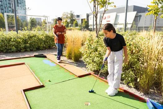 Mother and her little daughter practicing to hit the ball at the course photo