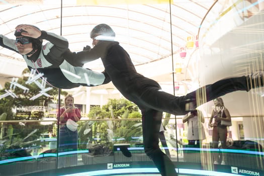 Excited teenage girl in helmet flying in aerodynamic tube wind tunnel. Skydiving training. photo