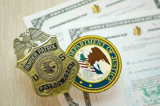 KYIV, UKRAINE - MARCH 9, 2024 US Border Patrol Agent badge and Department of Justice seal on United States Certificate of Naturalization photo
