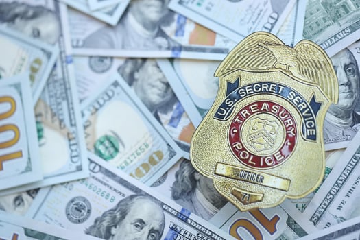 KYIV, UKRAINE - MARCH 9, 2024 US Treasury Police Secret Service Officer badge on many US hundred dollar bills photo