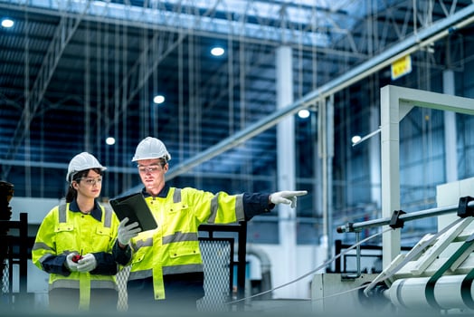 Male and female engineers in neat work clothes prepare and control the production system of large modern machines in a factory producing industrial technology products. photo