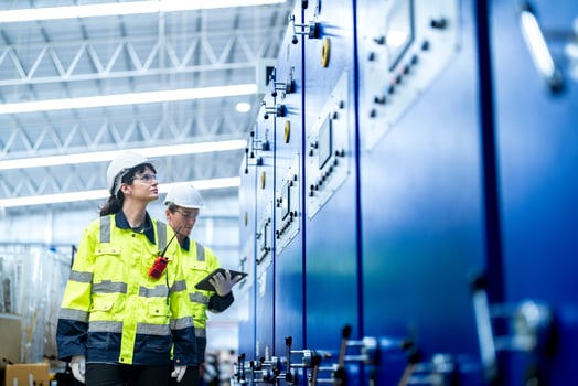 Male and female engineers in neat work clothes prepare and control the production system of large modern machines in a factory producing industrial technology products. photo