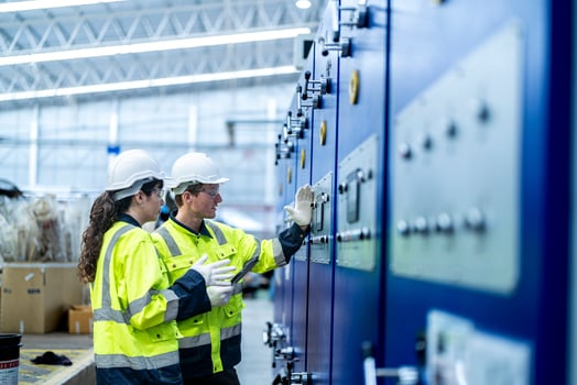 Male and female engineers in neat work clothes prepare and control the production system of large modern machines in a factory producing industrial technology products. photo