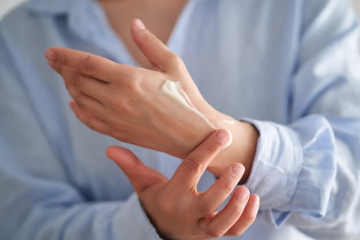 Hands in a blue shirt smear cream. photo