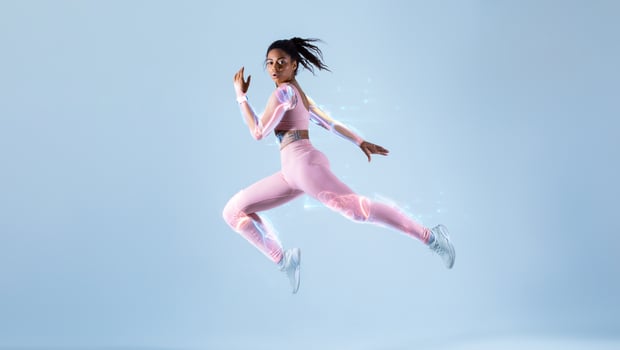 Training with modern futuristic sport technologies concept. Fit black woman in sportswear jumping or running, exercising on neon blue studio background, free space, full length. Energy and sport photo