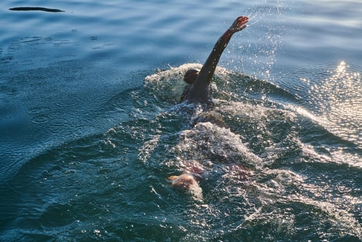 Triathlon athlete swimming on lake in sunrise wearing wetsuit photo