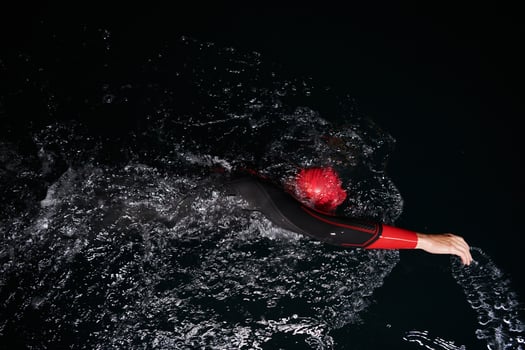 A determined professional triathlete undergoes rigorous night time training in cold waters, showcasing dedication and resilience in preparation for an upcoming triathlon swim competition photo