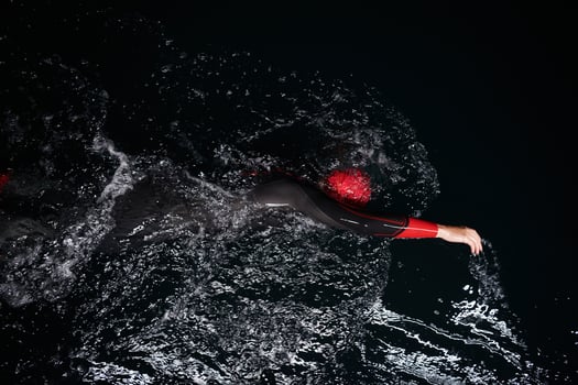 A determined professional triathlete undergoes rigorous night time training in cold waters, showcasing dedication and resilience in preparation for an upcoming triathlon swim competition photo