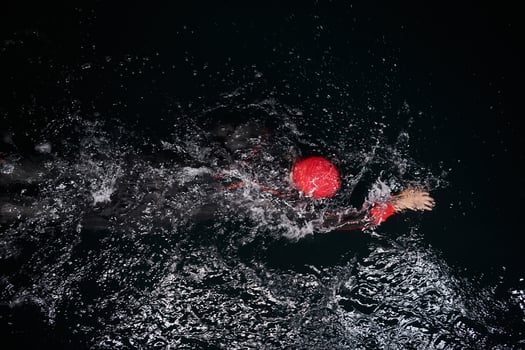 A determined professional triathlete undergoes rigorous night time training in cold waters, showcasing dedication and resilience in preparation for an upcoming triathlon swim competition photo