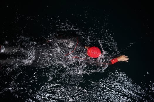 A determined professional triathlete undergoes rigorous night time training in cold waters, showcasing dedication and resilience in preparation for an upcoming triathlon swim competition photo
