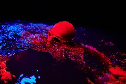 authentic triathlete swimmer having a break during hard training on night neon gel light photo