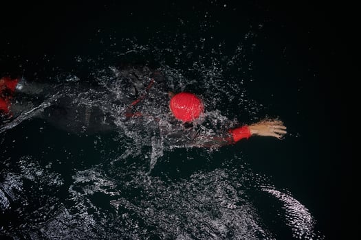 A determined professional triathlete undergoes rigorous night time training in cold waters, showcasing dedication and resilience in preparation for an upcoming triathlon swim competition photo