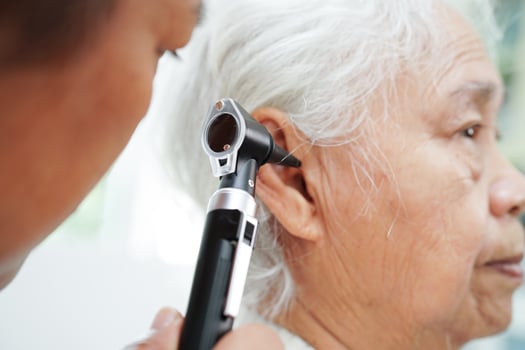 Otolaryngologist or ENT physician doctor examining senior patient ear with otoscope, hearing loss problem. photo
