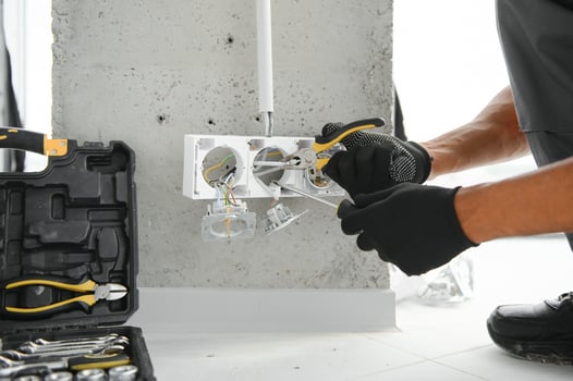 African American electrician replacing socket in room photo