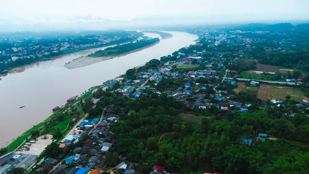 Aerial view of the mighty Mekong River winding from Chiang Khong, showing the vastness and beauty of the muddy waterway contrasting with the surrounding lush mountains and Laos villages. photo