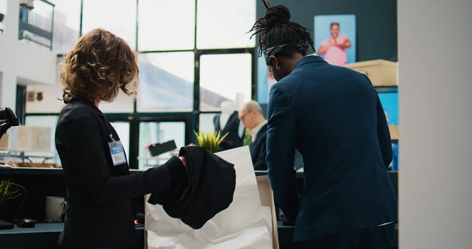 Store employees resupplying fashion boutique with merchandise, emptying box filled with clothing items from the new designer collection. Team of assistants registering clothes at checkout. Camera B. photo