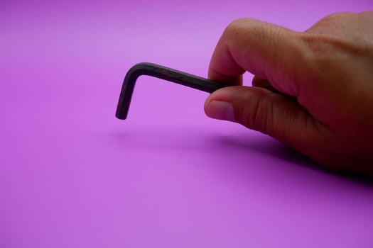 hand holding an L key. Allen key isolated on purple background photo