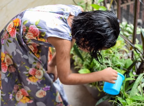 Cute 5 year old Asian little girl is watering the plant in the pots located at house balcony, Love of sweet little girl for the mother nature during watering into plants, Kid Planting photo