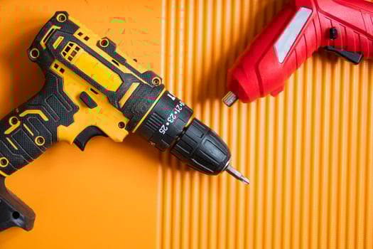 Cordless drill and screwdriver on orange surface photo