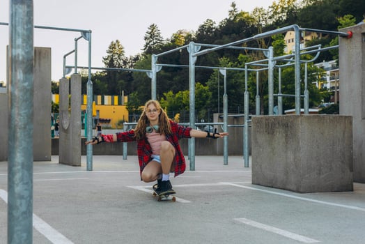 Teen girl skater with a skateboard is sitting and resting in the skaters park photo
