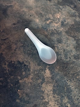 Single white plastic spoon lying on rough floor photo