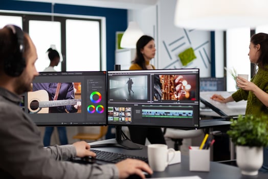 Creator content wearing headphones editing film montage in post production software at computer with dual monitors setup. Videographer cutting and prosessing movie footage in creative agency office photo