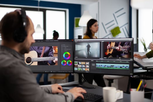 maker listening music at headphones editing movie using post production software working in creative agency office. Videographer processing audio film montage on computer in multimedia company photo