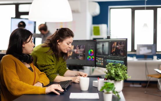 Team of women videographers working with modern post production software in digital multimedia company, looking at graphs in clipboard. maker employees processing film montage in creative agency photo
